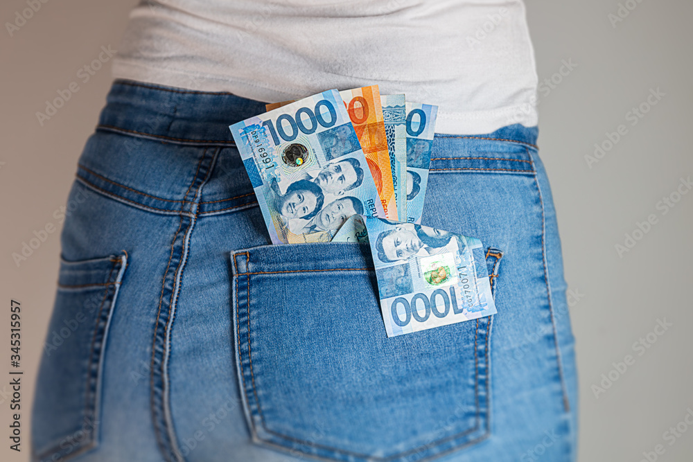 Philippines Peso in a female pants pocket. Philippine pesos notes stuck in a woman jeans pocket
