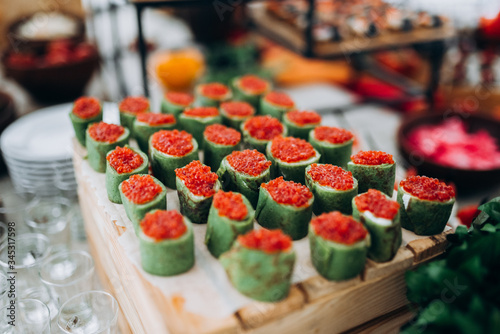 Rolls pieces with red caviar. Green rolls on the buffet table.