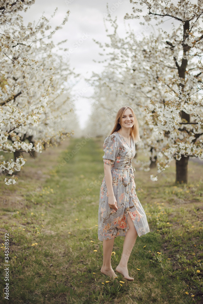 Beautiful girl in a flowering garden. Cherry garden. Summertime Concepts. Closeup Portrait of Positive. happy young woman enjoying smell in a flowering spring garden Beautiful girl in a flowering garden. Cherry garden. Summertime Concepts. Closeup Portrait of Positive. happy young woman enjoying smell in a flowering spring garden