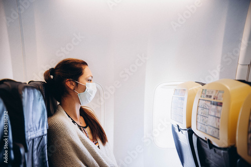 Woman in wearing mask flying in the airplaine. Felling temperature photo