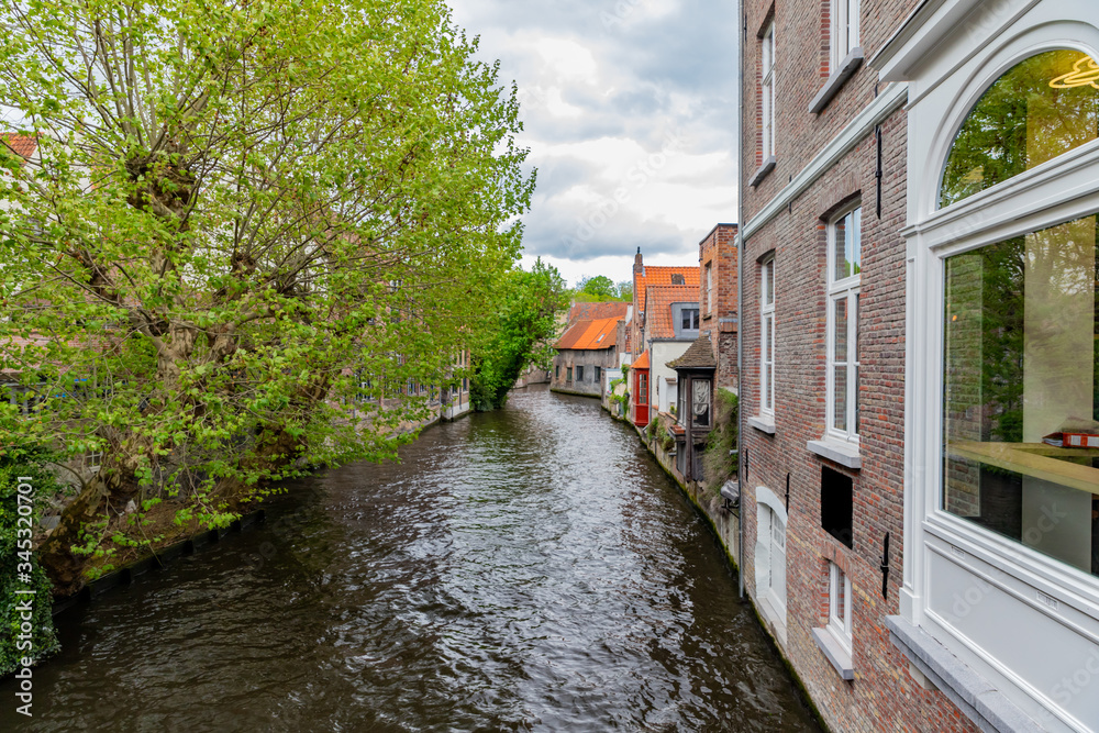 View of Dijver canal with house and trees in Bruges, Belgium