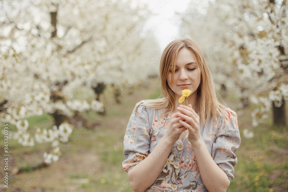 Beautiful girl in a flowering garden. Cherry garden. Summertime Concepts. Closeup Portrait of Positive. happy young woman enjoying smell in a flowering spring garden Beautiful girl in a flowering garden. Cherry garden. Summertime Concepts. Closeup Portrait of Positive. happy young woman enjoying smell in a flowering spring garden