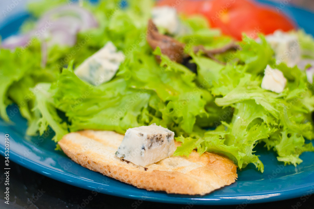 Salad with octopus or squid, cheese, tomato, olives, onions, spices and croutons, sauce or oil on blue plate