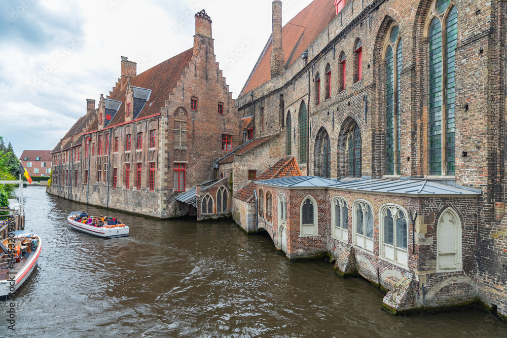 View of Dijver canal with canal boats, trees and traditional buildings in Bruges, Belgium