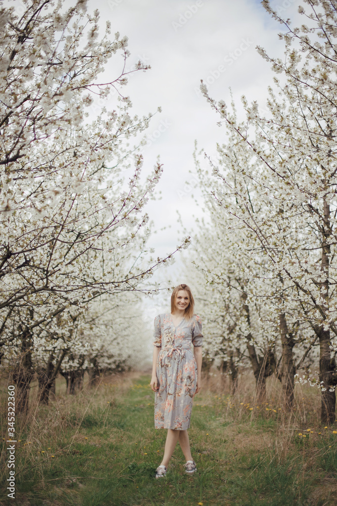 Beautiful girl in a flowering garden. Cherry garden. Summertime Concepts. Closeup Portrait of Positive. happy young woman enjoying smell in a flowering spring garden Beautiful girl in a flowering garden. Cherry garden. Summertime Concepts. Closeup Portrait of Positive. happy young woman enjoying smell in a flowering spring garden