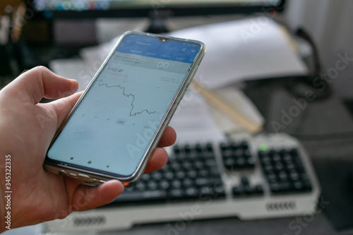 Businessman use smartphone in hand trading online Stock exchange market graph, selective focus with desktop computer on background
