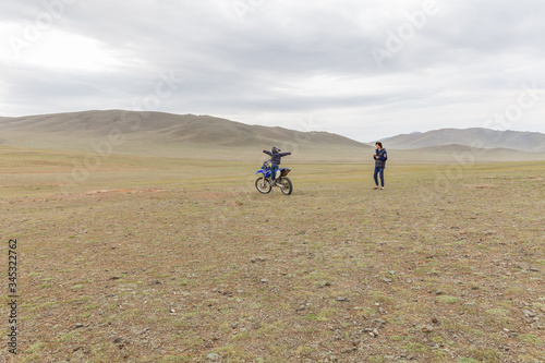  A father photographs a happy son who is sitting on a motorcycle in a helmet in Mongolian Altai