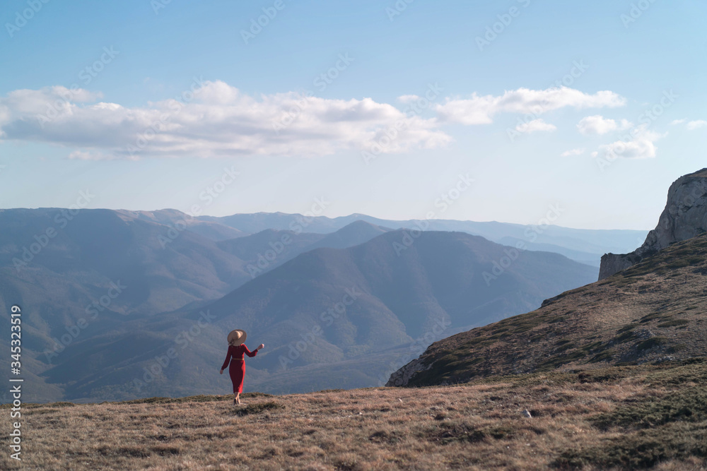 Young beautiful woman in a red dress looking at the mountains.