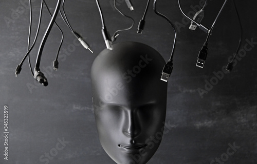 Digitalization, chipization, artificial intelligence, futuristic cyborg concept in total black color. Depersonalized human robot android face and many digital device wires cables chargers. photo