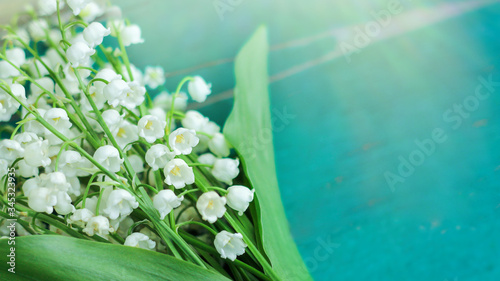 Beautiful bouquet of lilies of the valley on a wooden background, top view