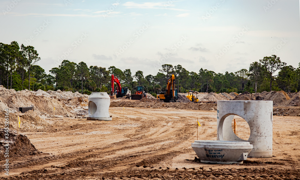 Heavy equipment sits idle at a new road under construction through a Florida pasture.

