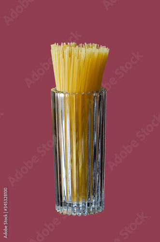 Unprepared pasta in a high faceted glass. photo