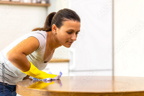 Close up photo of anxious girl polishing tabletop, making everything shine perfect, looking a major germophobe.