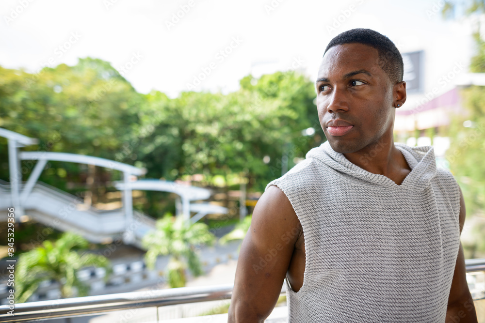 Fototapeta premium Young handsome African man thinking and ready for gym in the city