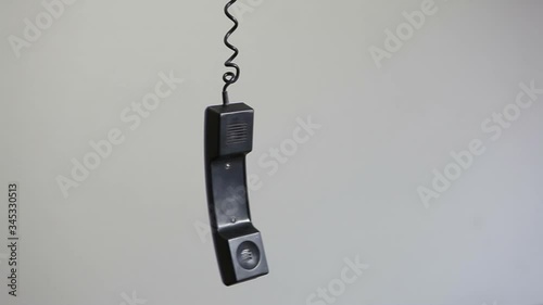 A landline handset hangs on a wire. photo