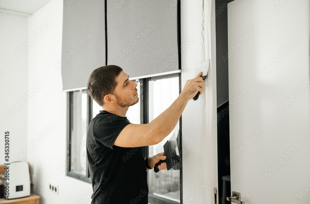 A portrait of a man in an apartment is repairing, plastering and plastering a doorway into a room. Household chores. A portrait of a man in an apartment is repairing, plastering and plastering a doorway into a room. Household chores.