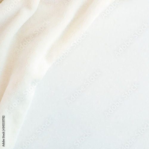 Soft cozy plush fabric with a pile lies in beautiful folds on white marble countertop background. Delicate flat lay.