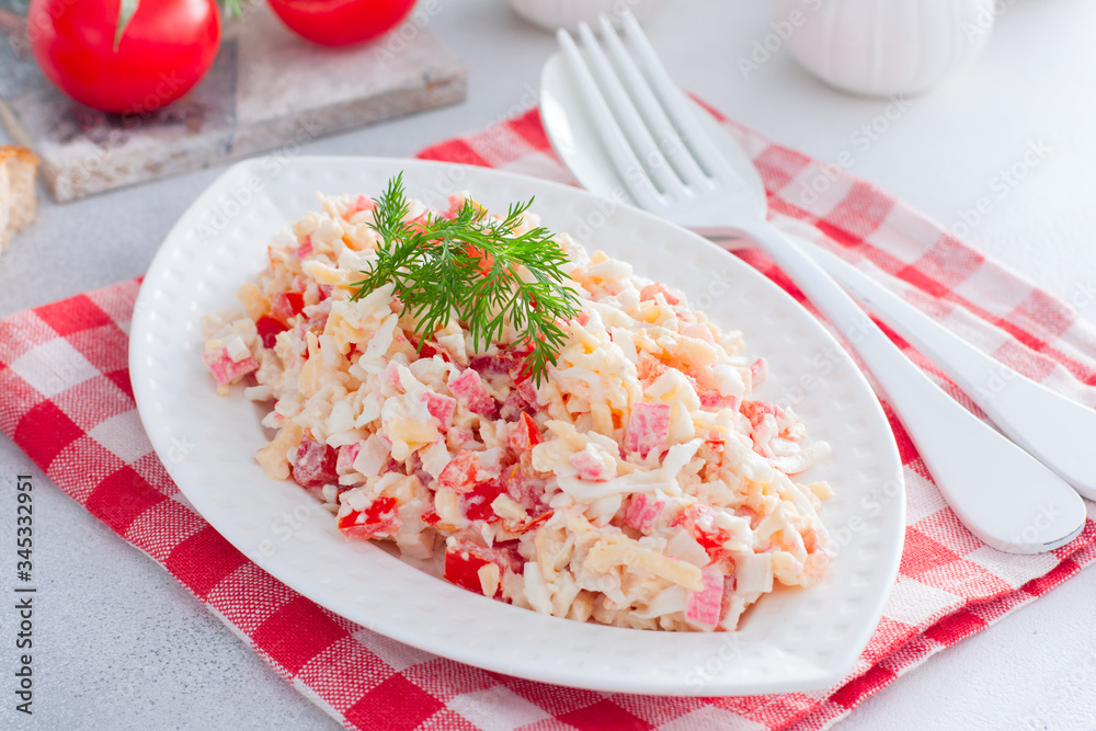 Homemade salad with crab sticks, tomatoes, cheese on a white dish, horizontal Homemade salad with crab sticks, tomatoes, cheese on a white dish, horizontal