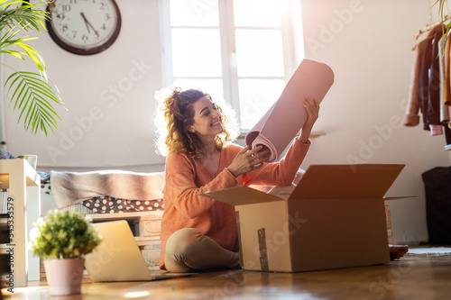 Woman unpacking box with workout equipment at home 
 photo