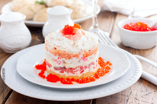 Holiday salad with red fish, shrimp, crab sticks, vegetables and red caviar, selective focus