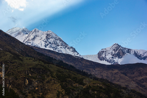 Sunlight streams across the sky above the snow covered Himalayan peak of Mount Dhaulagiri and its icefall on the Annapurna Circuit trekking trail in Nepal.