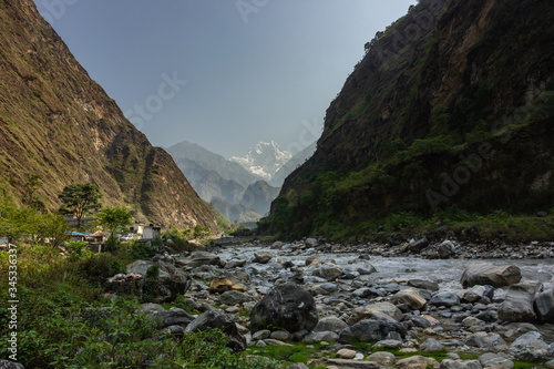 A distant, hazy view of the snow covered HImalayan peak of Nilgiri South from the banks of the Kali Gandaki river in the village of Tatopani in Nepal.