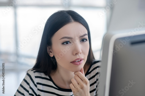 Brunette woman in a striped shirt looking concentrated