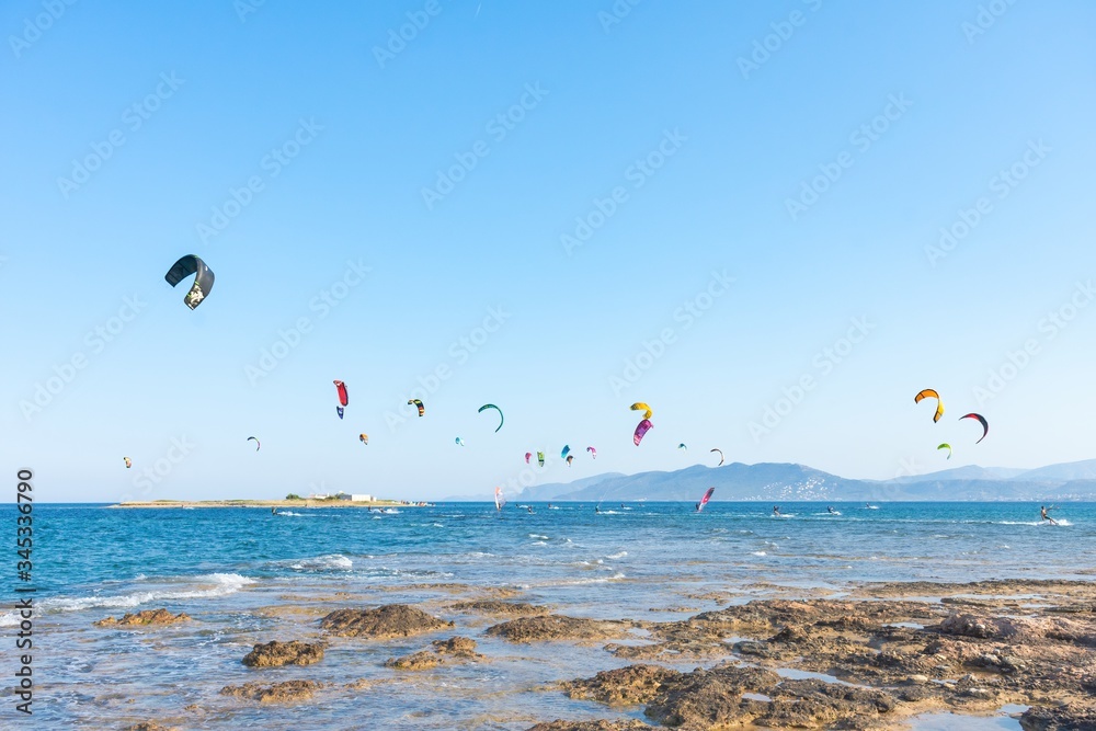 Kitesurfers with colorful kites having fun in Loutsa Greece on a sunny summer day, horizontal