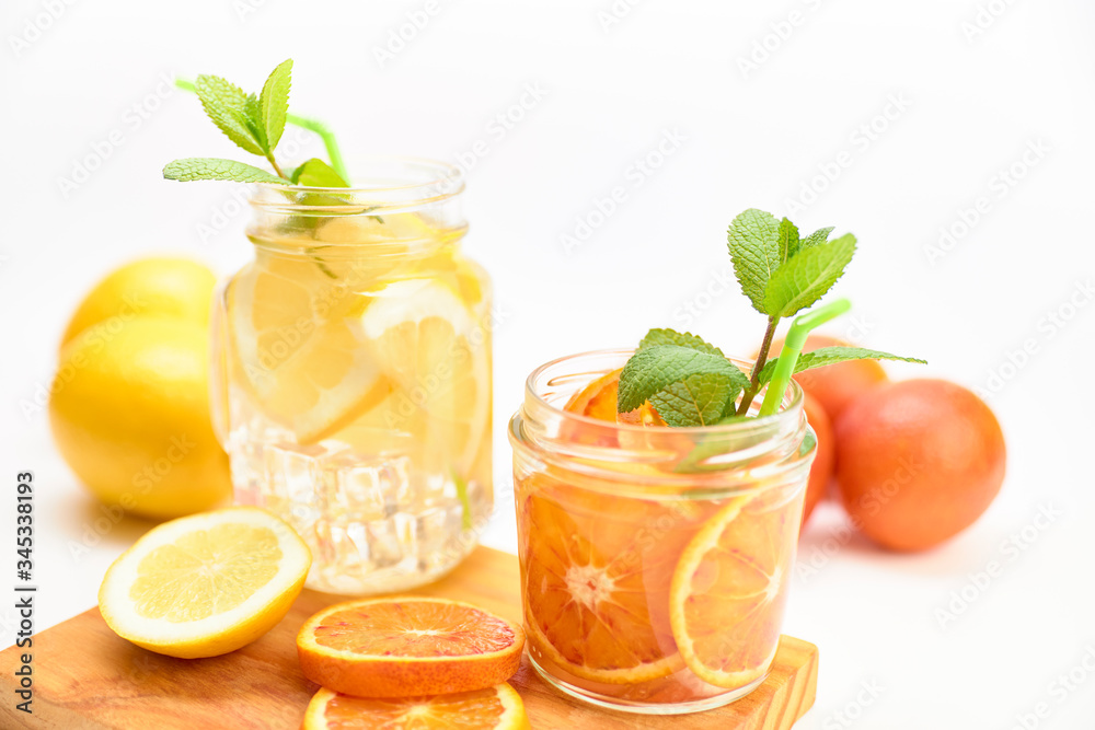 Pitcher and glass of homemade lemonade and orangeade with some mint leaves Pitcher and glass of homemade lemonade and orangeade with some mint leaves