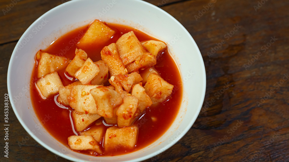 Korean Radish Kimchi in white bowl on wood table for food content. Korean Radish Kimchi in white bowl on wood table for food content.