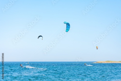Kitesurfers with colorful kites having fun in Loutsa Greece on a sunny summer day, horizontal