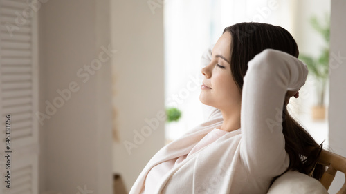 Close up of peaceful millennial Caucasian girl sit relax in armchair at home sleeping or taking nap, calm young woman rest in comfortable chair, fall asleep daydream indoors, stress free concept