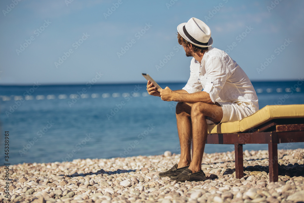 Man relaxing and use digital tablet at sea beach