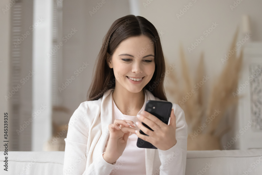 Smiling Caucasian millennial girl using modern smartphone gadget, browsing wireless internet at home, happy young woman texting messaging on cellphone device, shopping online, technology concept Smiling Caucasian millennial girl using modern smartphone gadget, browsing wireless internet at home, happy young woman texting messaging on cellphone device, shopping online, technology concept