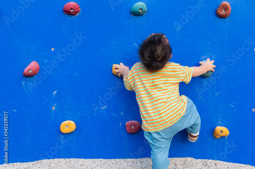 Asian baby climbing up the climbing wall