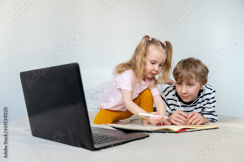 Kids studying at home using laptop and book