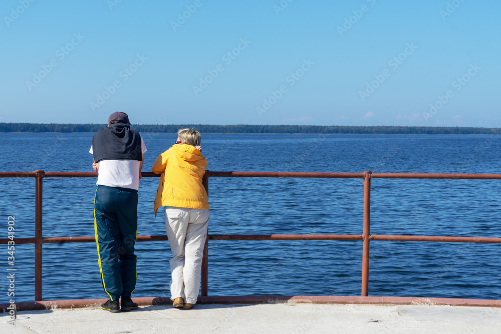 A man and a woman stand with their backs to the camera and look at the seascape. A man and a woman stand with their backs to the camera and look at the seascape.