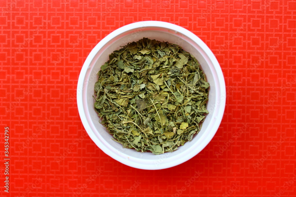 Kasuri Methi or dried fenugreek leaves in a plastic bowl Kasuri Methi or dried fenugreek leaves in a plastic bowl
