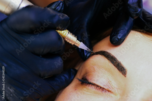 master brow artist makes permanent eyebrow makeup in the technique of powder browsers. Semi-permanent make-up