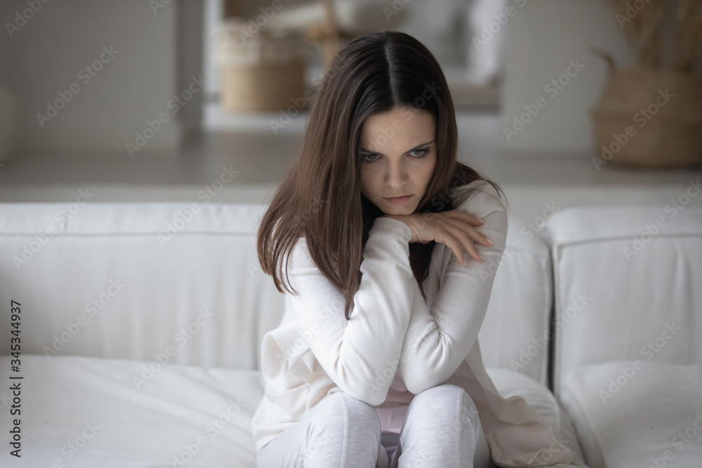 Unhappy millennial girl sit on couch at home lost in thoughts suffering after breakup or marriage dissolutions, upset young woman feel depressed stressed with mental psychological problems Unhappy millennial girl sit on couch at home lost in thoughts suffering after breakup or marriage dissolutions, upset young woman feel depressed stressed with mental psychological problems