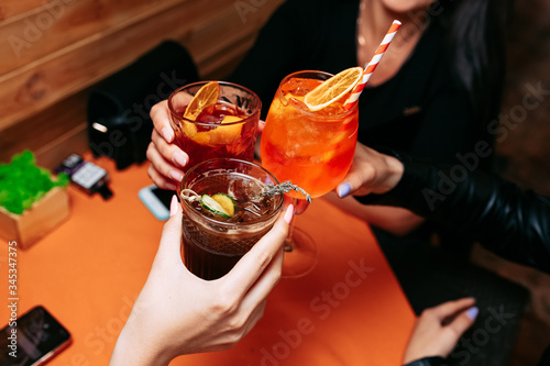 three girls clink glasses with summer alcoholic Cocktail.