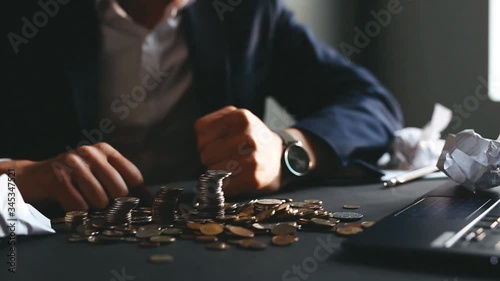 Depressed businessman has lost his business and punches in the stacks with coins. Destroyed businessman. The concept of business loss, bankruptcy and crisis.