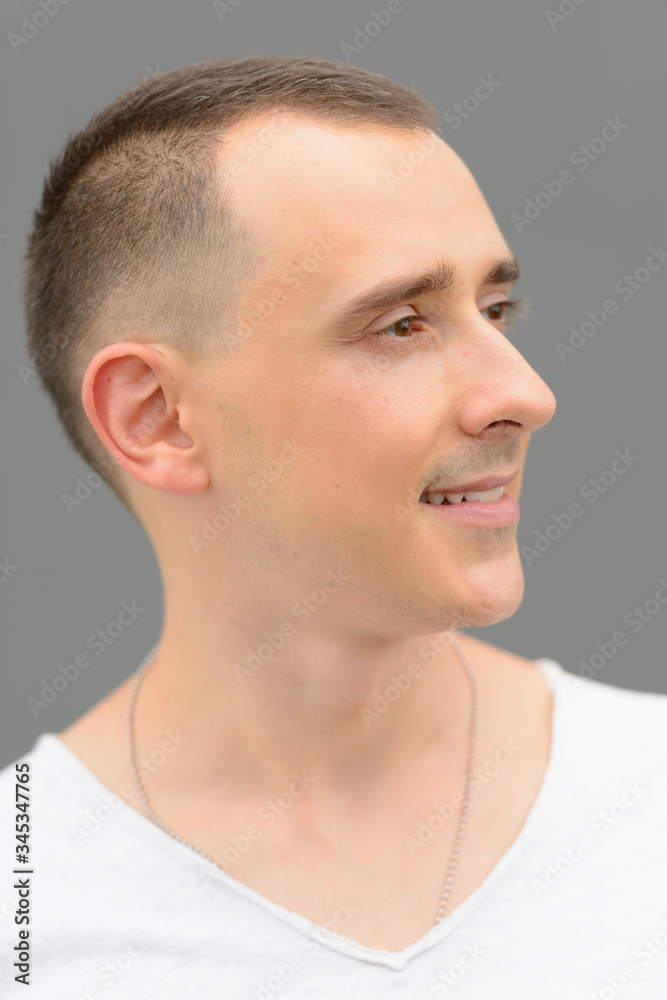 Fototapeta premium Face of happy handsome man thinking against gray wall