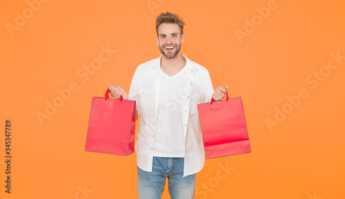guy happy about his purchase. successful shopping online. male shopper hold packages. shopping bag with goods. How to save money while sale. cyber monday concept. goods for men
