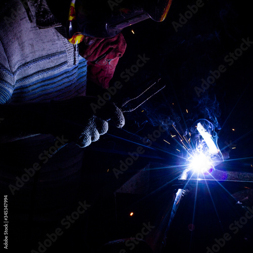 welder doing metal work at night, front and background blurred with bokeh effect