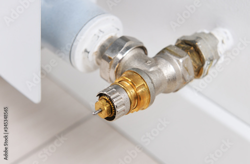 Thermostatic valve or valve - the main component is installed on the heating radiator in the apartment.Thermostatic regulator on a water heating radiator in an office room. Side view.