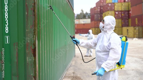 People wearing protective suits spray disinfectant chemicals on the cargo container to prevent the spreading of the coronavirus.