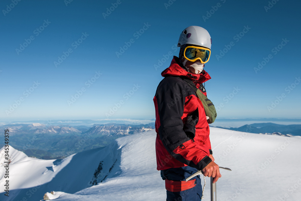 climber in a red jacket stands on top of a mountain
