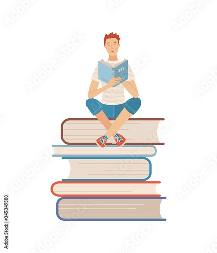 Young man reading book while sitting on stack of books