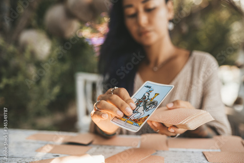 Bild auf Leinwand Woman is reading Tarot cards sitting at the table outdoors
